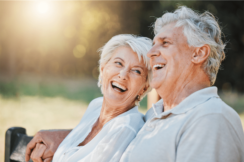 Senior couple laughing together on a garden bench