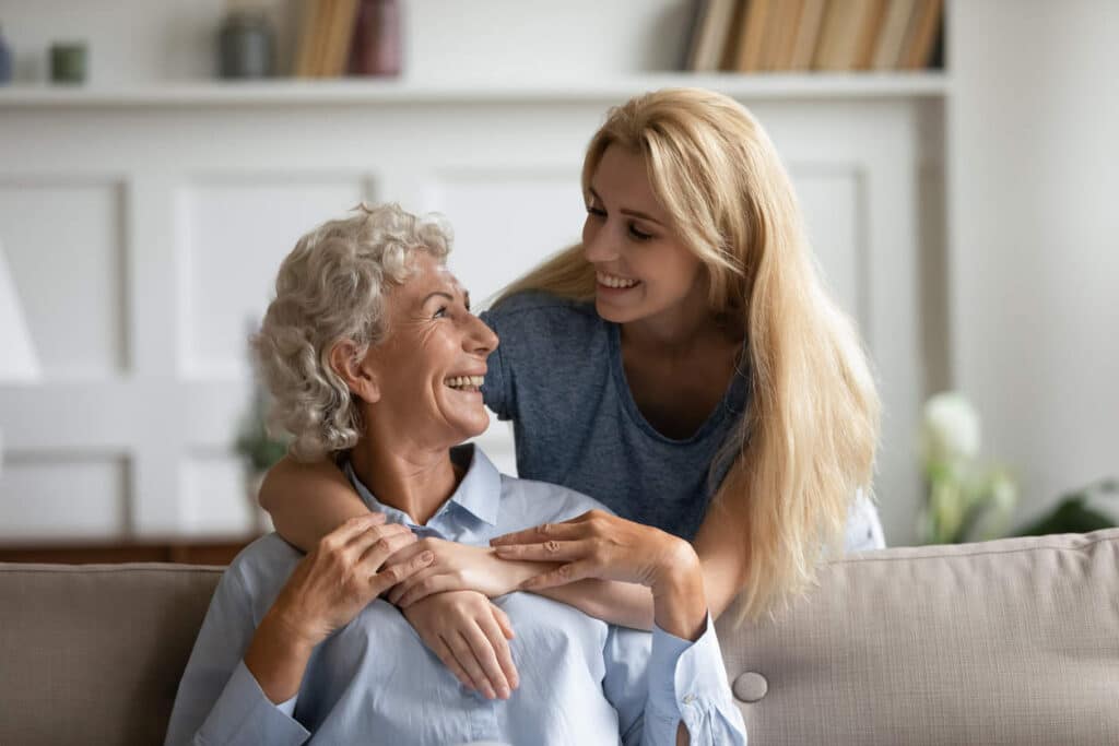 Senior mother and adult daughter hugging in the living room