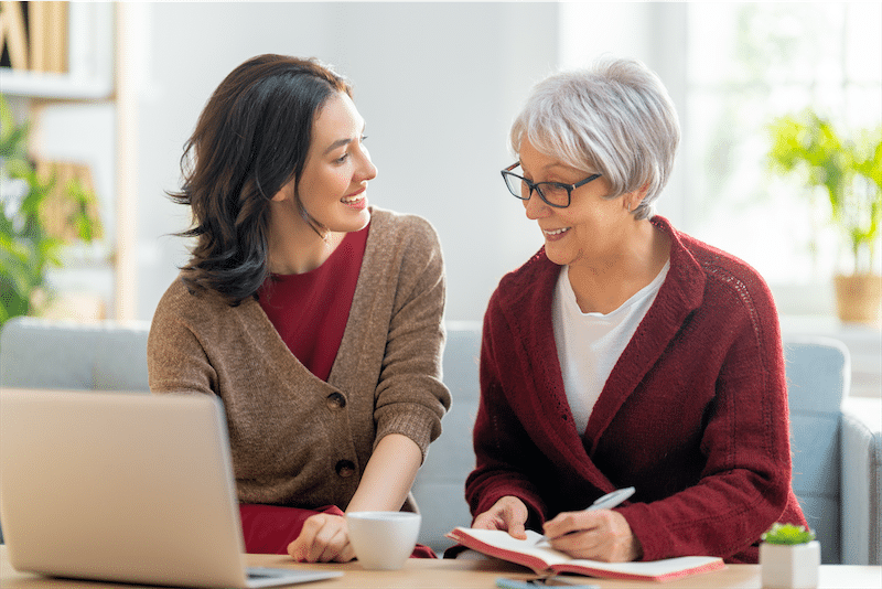 Two women on a sofa reviewing a receipt and planning a household budget