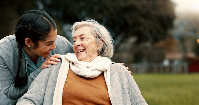 Caregiver outside with a senior woman smiling